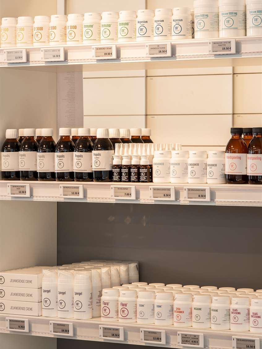 Rekken met bereidingen in flessen en potjes bij Apotheek Debaene